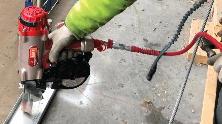 Person using pneumatic concrete nailer