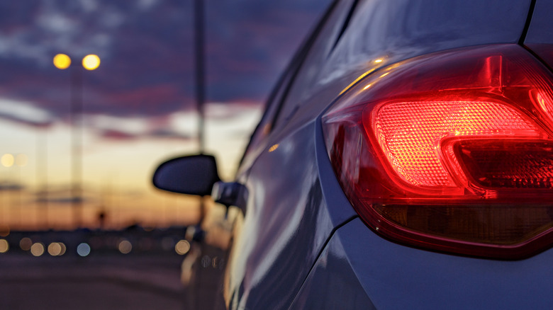 Tail light of a car against a blurred sunset.
