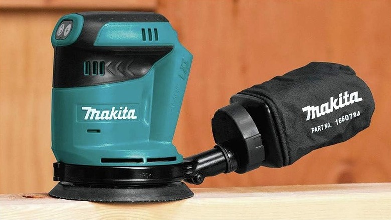 A closeup of Makita orbit sander connected to a dust bag.
