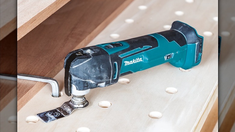 Using a multi-tool on a wooden surface.