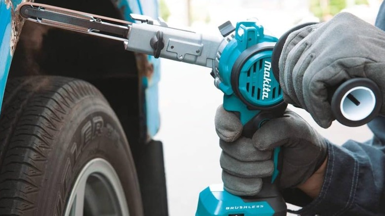 using a Makita detail belt sander on a car