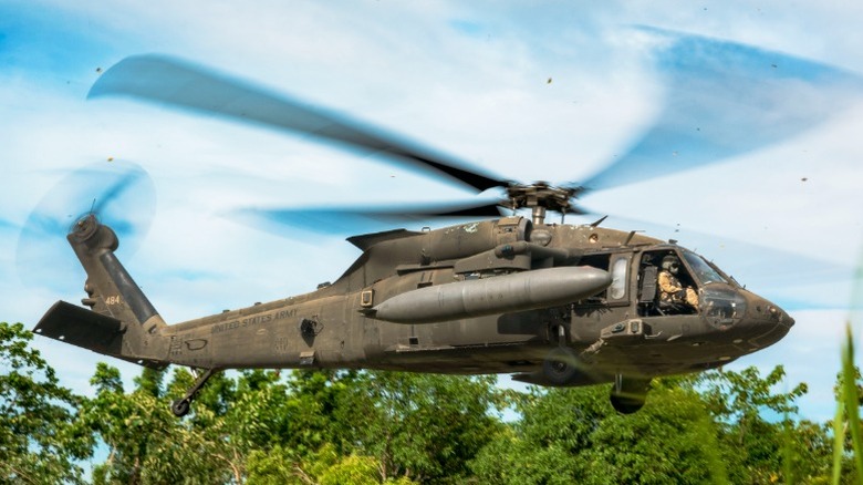 U.S. Army Sikorsky UH-60 Black Hawk helicopter hovering in wooded area