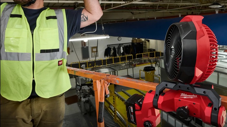 worker with the scissor lift fan near him