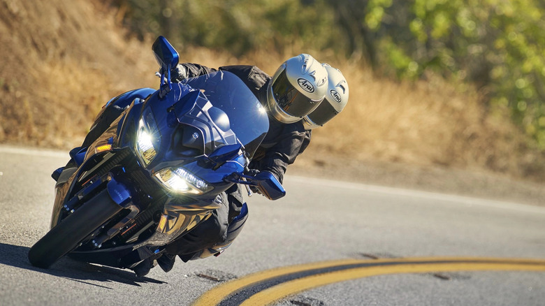 Two riders leaning into a corner on a blue Yamaha FJR 1300 ES.