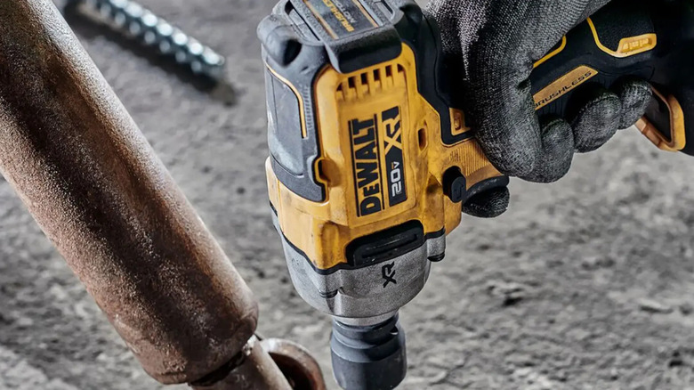 The DeWalt 1/2 inch DR Mid Range Impact Wrench held by gloved hand.