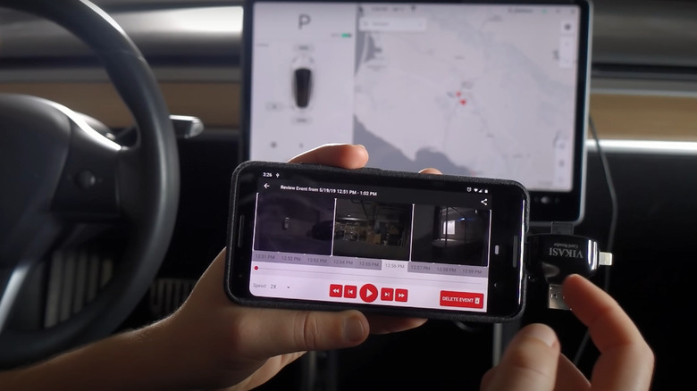 A person holding up a phone with the Sentry Reviewer app running inside a tesla vehicle