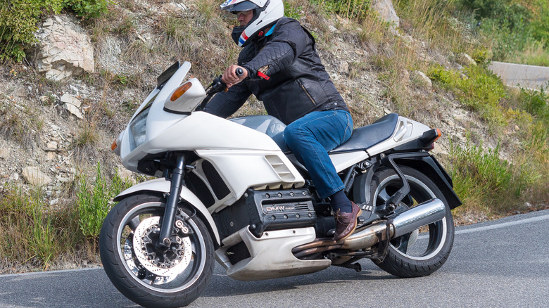 A late model year BMW K100 from 1986 taking a bend on a hilly mountain road.