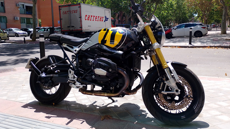 A yellow and black bMW R nineT standard motorcycle parked at the side of a road.