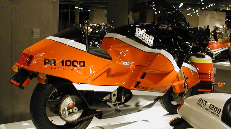 An RR 1000 Battletwin sitting in a museum among other motorcycles, under lights.
