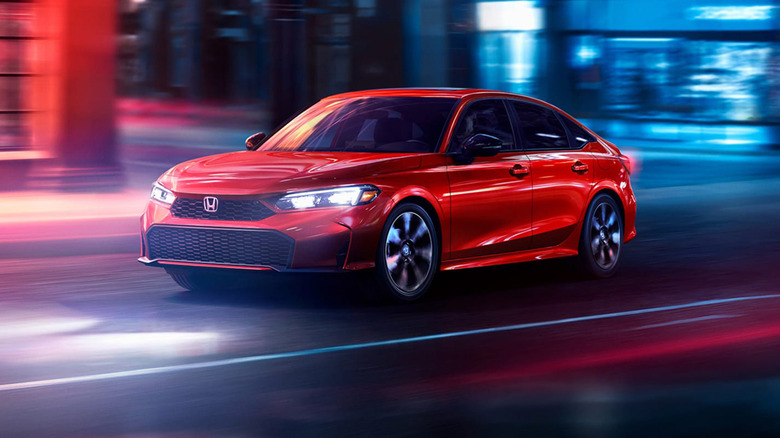 A red Honda Civic driving down a city street.