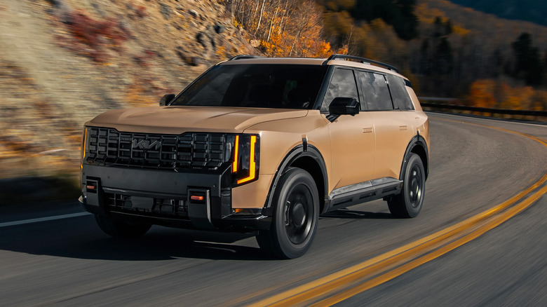 A brown Kia Telluride driving on a twisty mountain road.