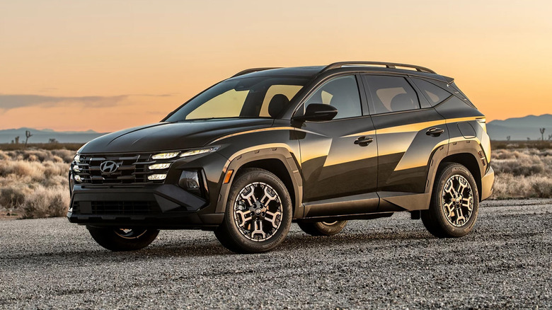 A black Hyundai Tucson parked on a gravel road at sunset.