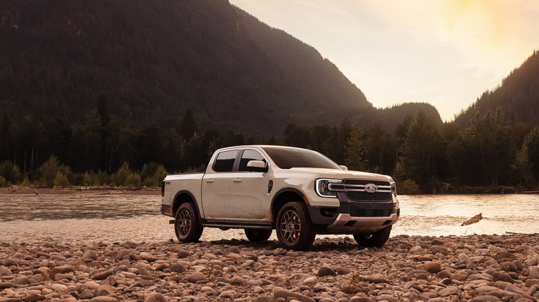 A white Ford Ranger parked next to a mountainous lake.