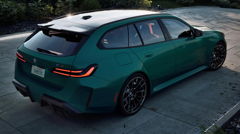 A BMW M5 Touring in teal driving down a road