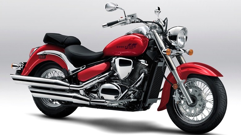 A Suzuki Boulevard C50 cruiser motorcycle in a shiny red color, displayed in a studio setting with a plain background too.