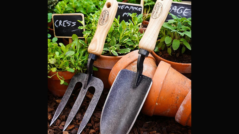 A small fork and spade for gardening in front of pots