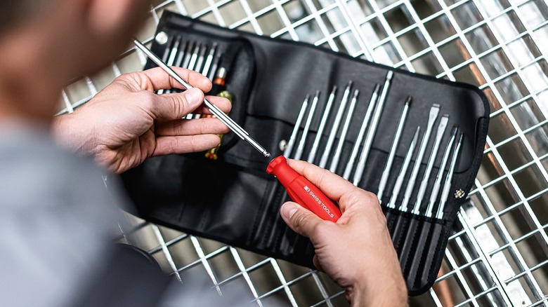 person holding screwdriver handle with shaft