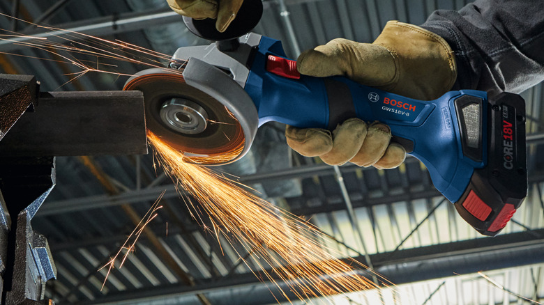 A worker using a Bosch cordless angle grinder with an 18V CORE battery.