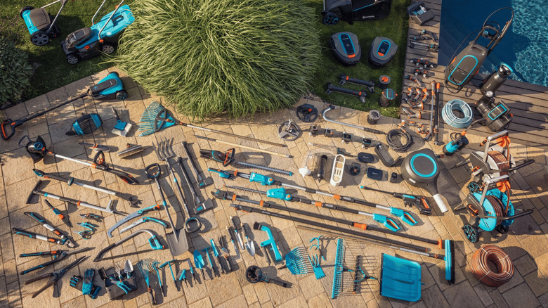 Wide overhead view of a full lineup of Husqvarna gardening and outdoor tools arranged on a patio.