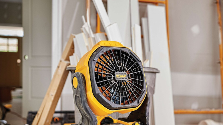 A DeWalt jobsite fan on a table inside a building in construction.