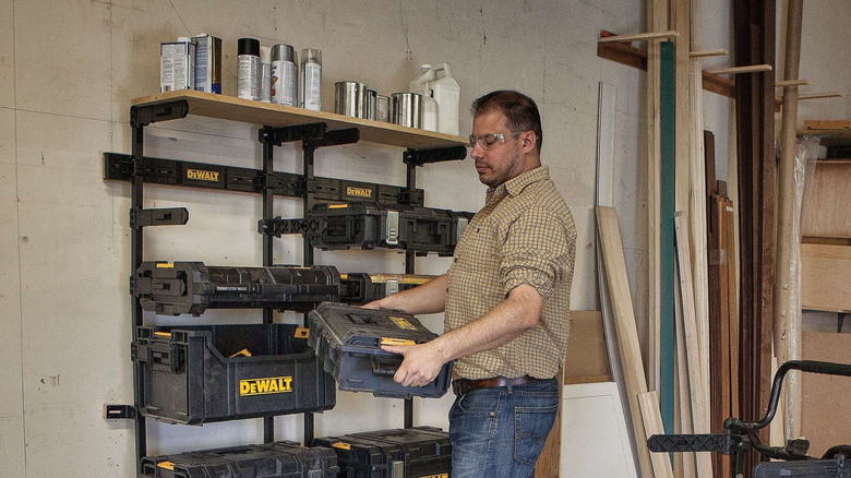 A man organizing DeWalt ToughSystem toolboxes on a mounted Workshop Racking System inside a woodshop.