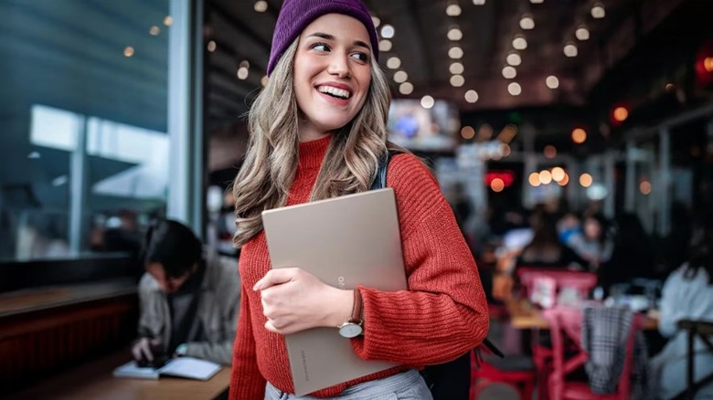 woman smiling and holding closed Lenovo Chromebook Plus 14