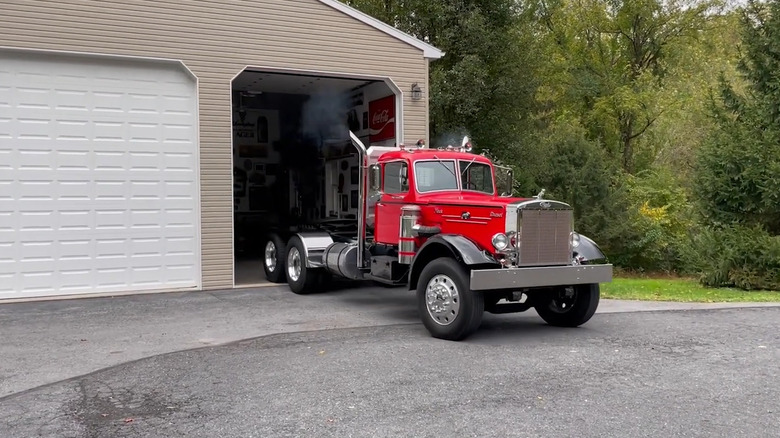 A gorgeous red and black 1952 Mack LTL truck pulling out of a garage