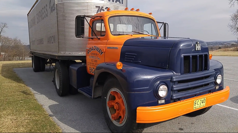 A yellow and blue chrome deleted International harvester R190 towing a silver trailer
