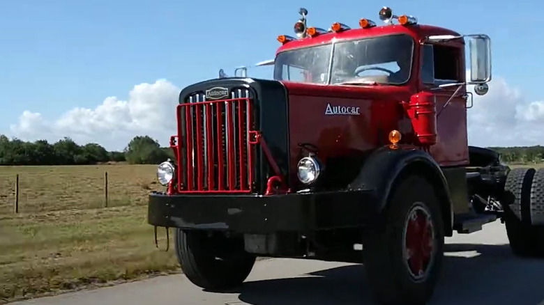 A red, restored DC 75 day cab truck driving down a highway