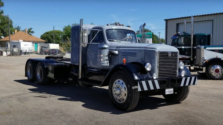 A black and silver restored international harvester westcoaster from 1957 driving by a garage