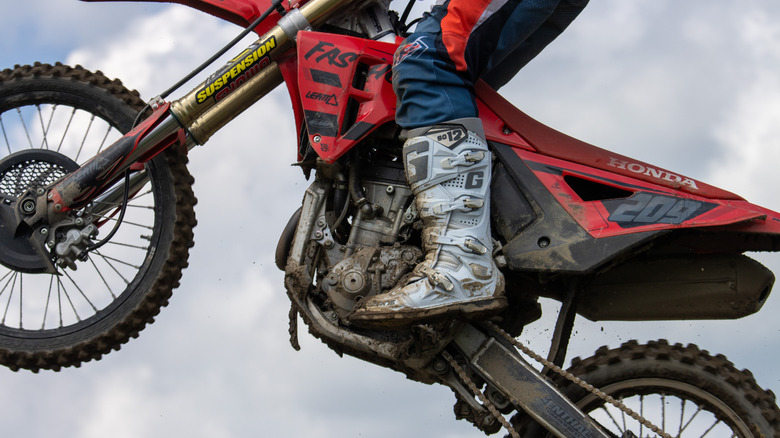 Rider on red motorcycle wearing white dirty boots