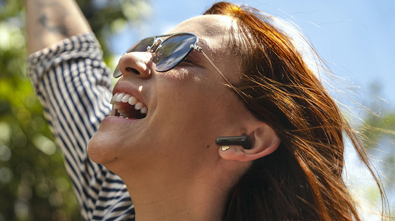 A woman laughing while wearing a wireless earbud