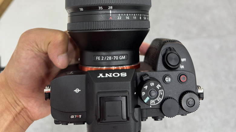 A person holding a Sony A7R camera with a 28-70mm lens attached