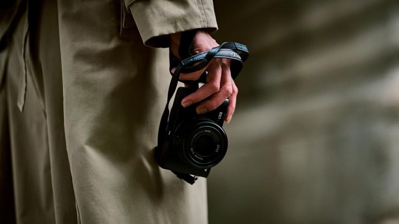 A person holding a Sony RX1R III camera with a strap