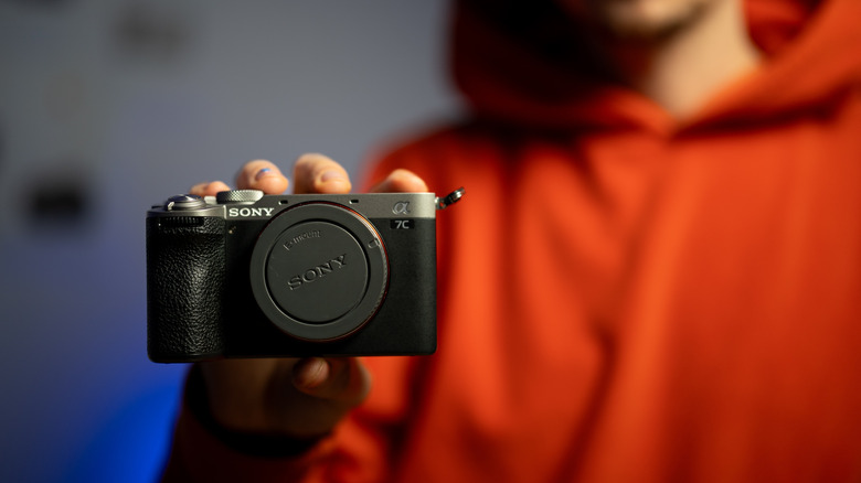 A person in a red hoodie holding a Aony A7C camera
