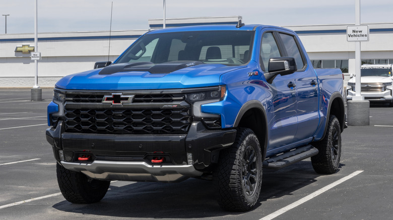 An opal-blue Chevrolet Silverado ZR2 with the factory mask and stickers still on parked in a lot