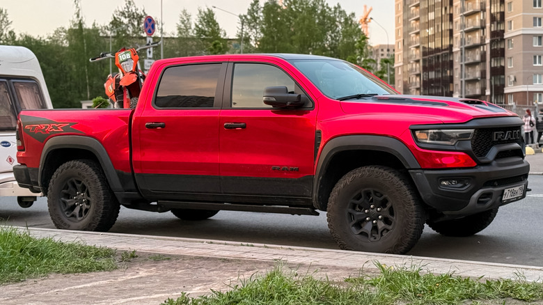 A supercharged RAM TRX with the 6.2 engine in red parked at the side of a narrow street