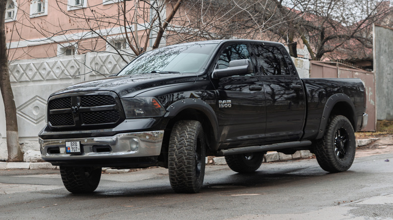 A fourth generation dodge RAM 1500 in black driving down an inside city street.