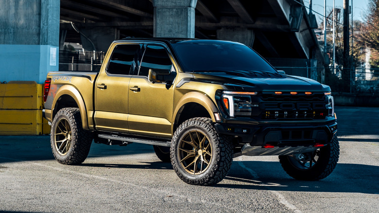 A golden 205 Ford Raptor R parked under a bridge, sun gleaming off the paint