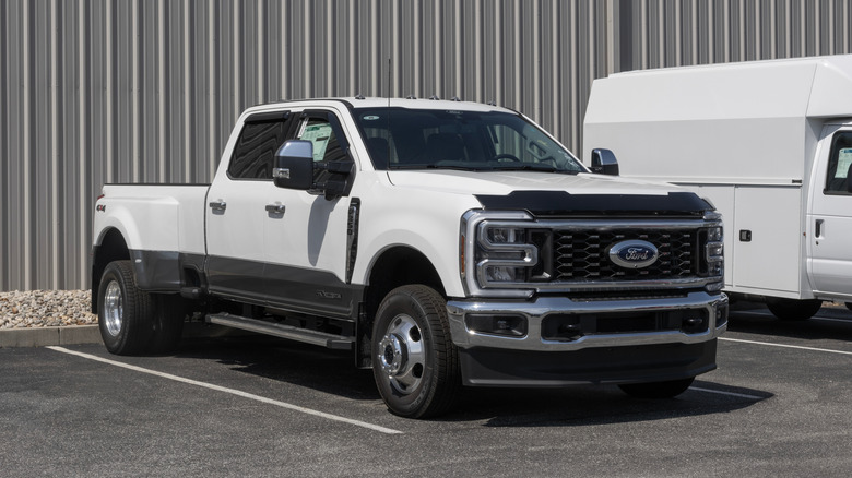 A white pearlescent Ford Super Duty pickup truck parked outside of a corrugated steel warehouse