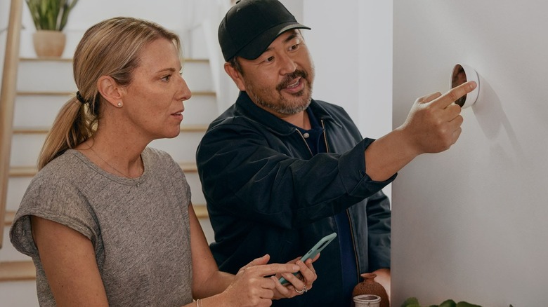 A man and woman operating a Google Nest Thermostat