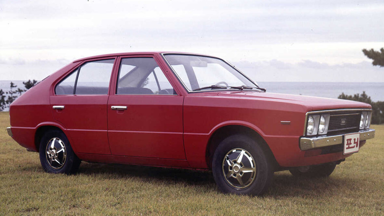 Red 1975 Hyundai pony parked in field