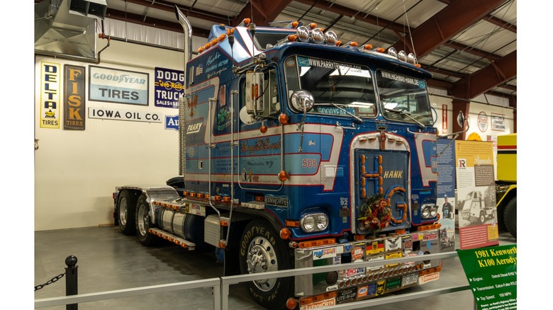 A custom black Kenworth cabover semi truck with chrome details and blue accents