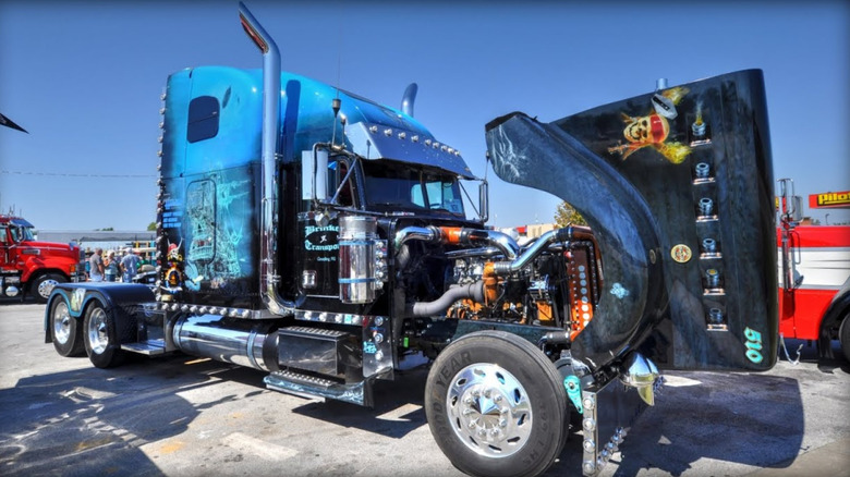 A custom semi truck with an elaborate pirate-themed paint job with skull artwork, glowing blue highlights, and chrome accents.