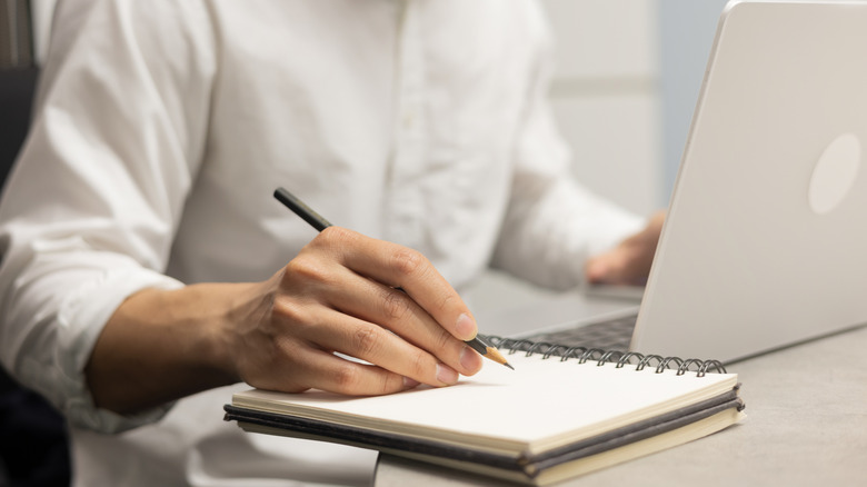 Closeup of a man making a list on a notepad