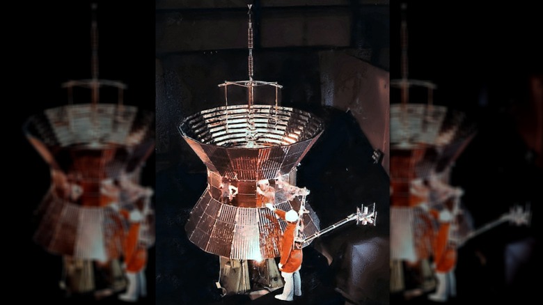 A technician stands next to one of the twin Helios spacecraft