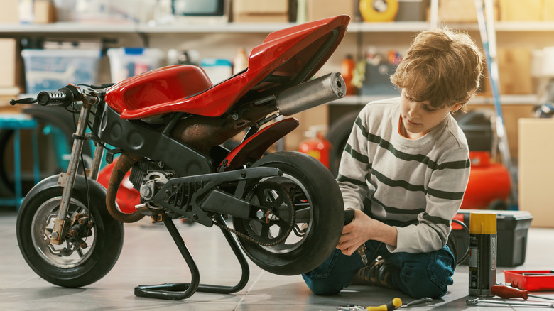 Young boy working on miniature motorcycle