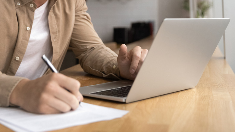 Closeup of man making a list from a laptop