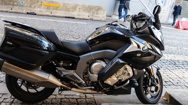 A black and Gold BMW K 1600 GT motorbike parked on pavement at the side of a road