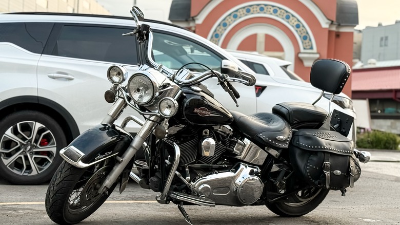 A black and silver Harley‑Davidson Heritage Classic parked next to a white car.